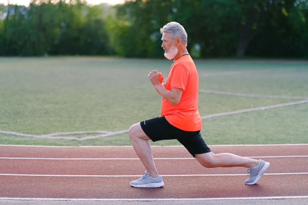 Man in sportswear doing a forward lunge on a running track